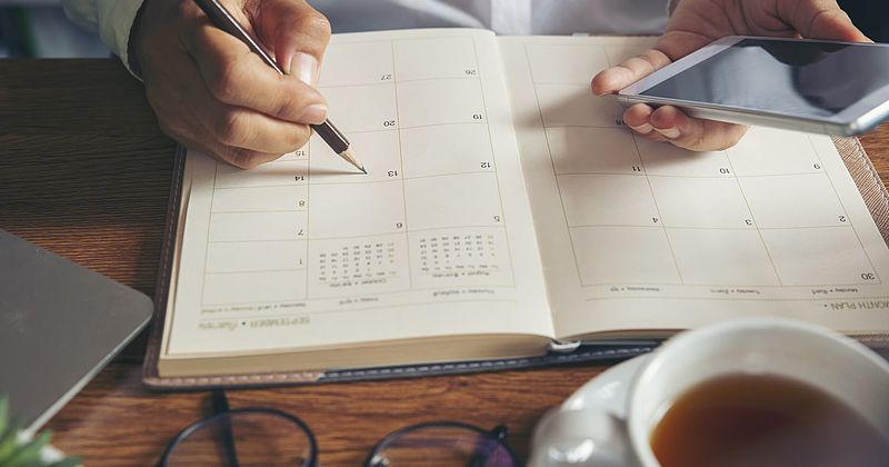 Person schreibt Termin in einen Kalender