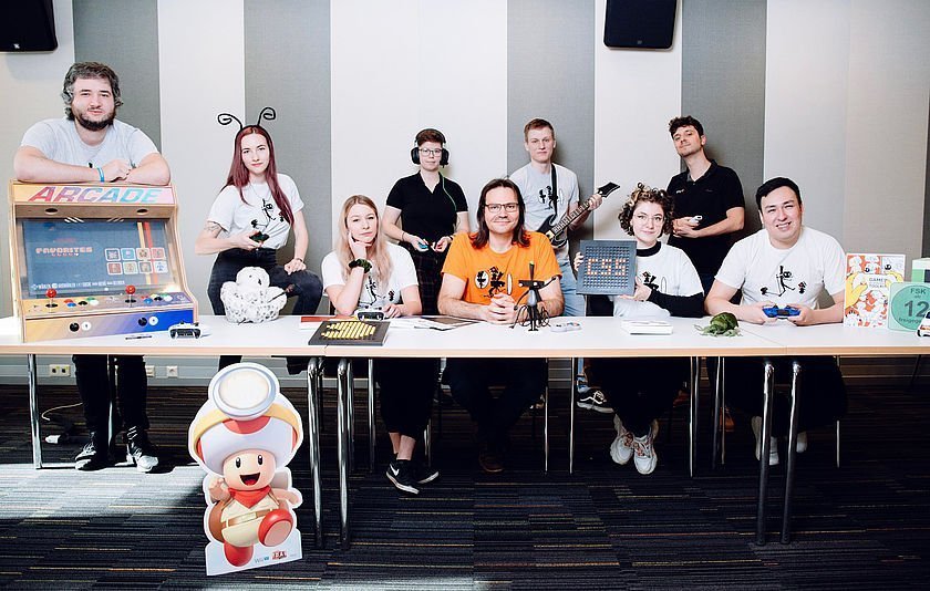 neun Personen mit Spiel-Elementen am Tisch