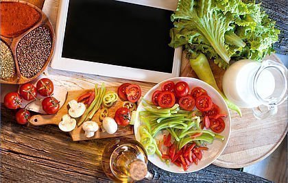 iPad, frisch geschnittenes Salatgemüse, Glaskrug voll Milch