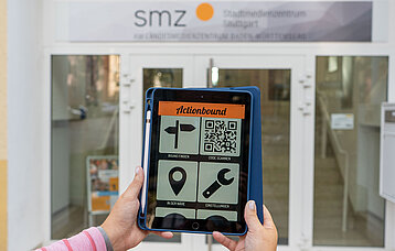 Tablet in Händen vor Eingangstür