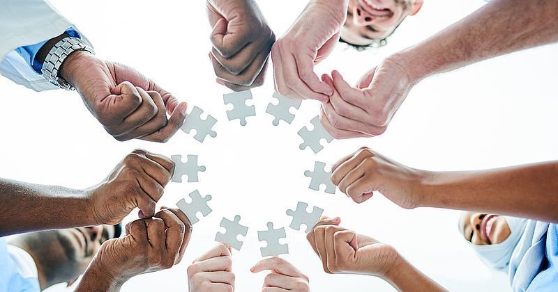 Hände mit Puzzleteilen bilden einen Kreis