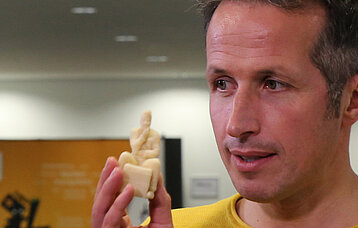 Mann hält eine Marzipanfigur aus dem 3D-Drucker in der Hander